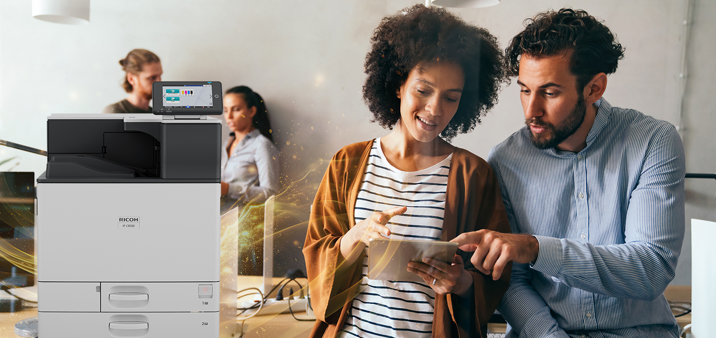 Ricoh IP C8500 Colour A3 printer for office use and two individuals collaborating at work with a tablet in a modern workspace.
